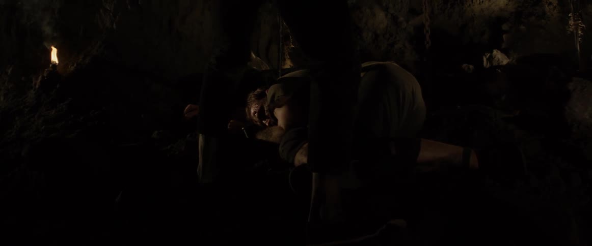 A man stands over an injured and bleeding man with a sword