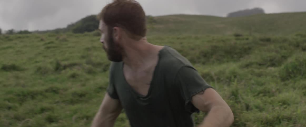 A man is running across a green meadow