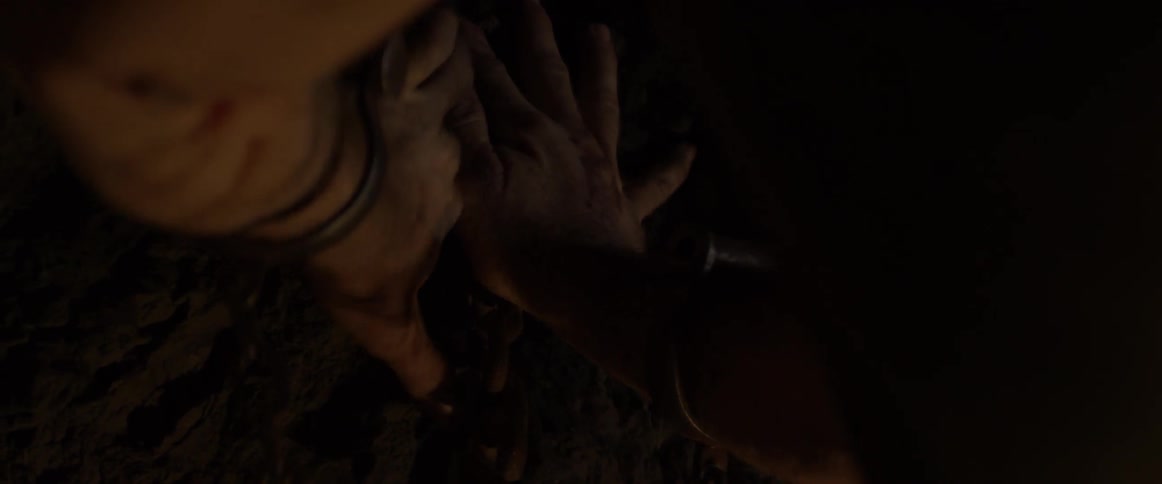 Two men struggle over chains in a cave