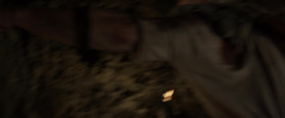 Bearded man swings his arm forcefully as another man is curled up on the floor