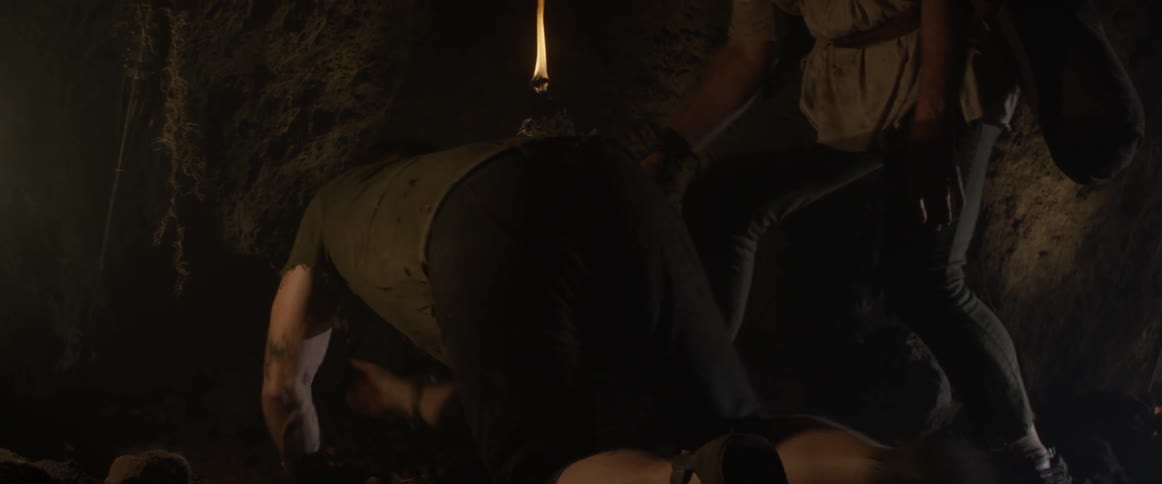 Man helps a bloodstained person up in a cave and grabs his arms