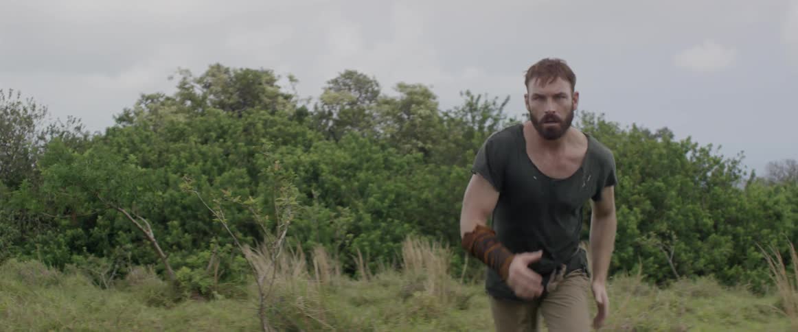 Angry man runs through tall grass on a cloudy day