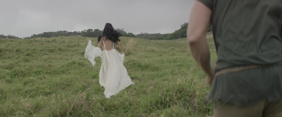 A woman runs across the green field and a man runs behind her