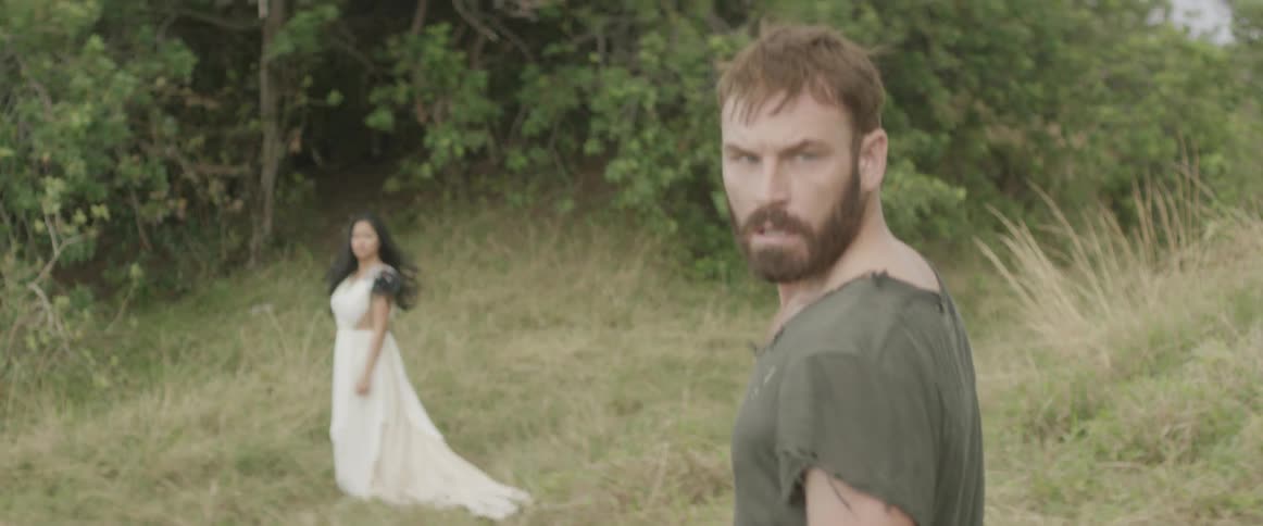 A man walks up to a woman by the woods and turns around