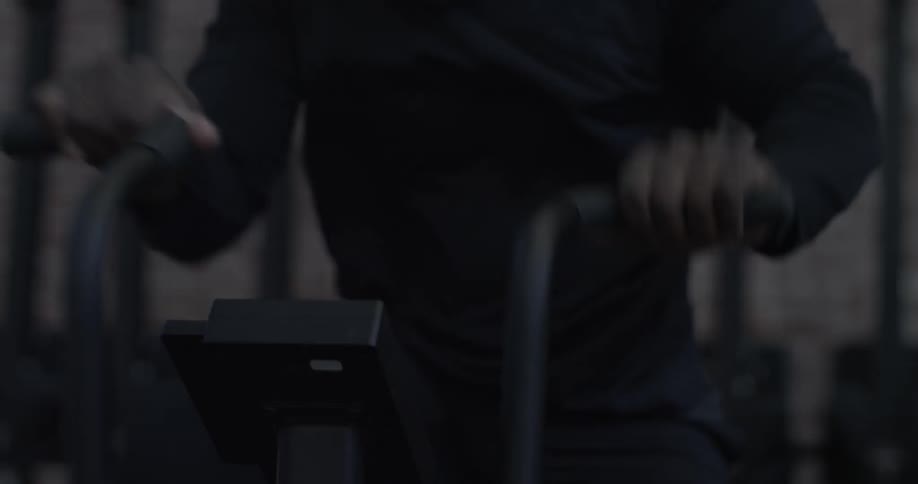 A male athlete is working out on a cargo bike in a gym