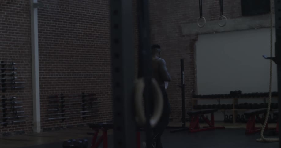 A man drinks from a water bottle as he walks across the gym
