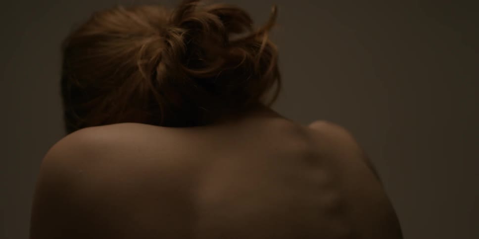 A naked woman is rolling her head and arching her shoulders