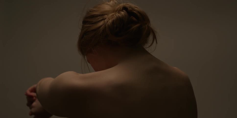 A woman without a shirt shrugs her shoulders
