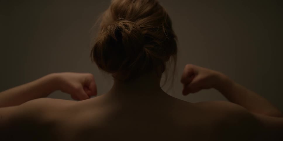 A woman lifts her hands up and clenches them into fists