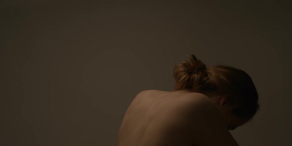 Woman looks down in a dimly lit room