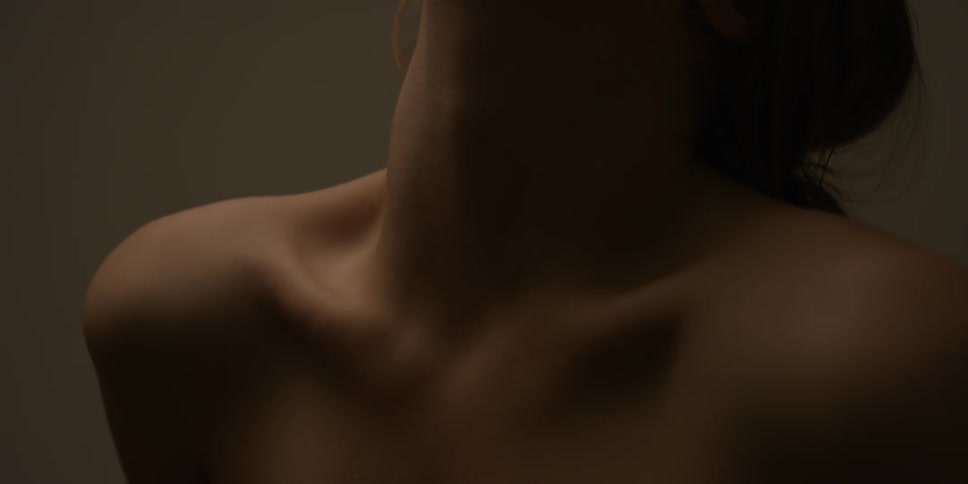 A naked woman rolls her neck back and arches it side to side