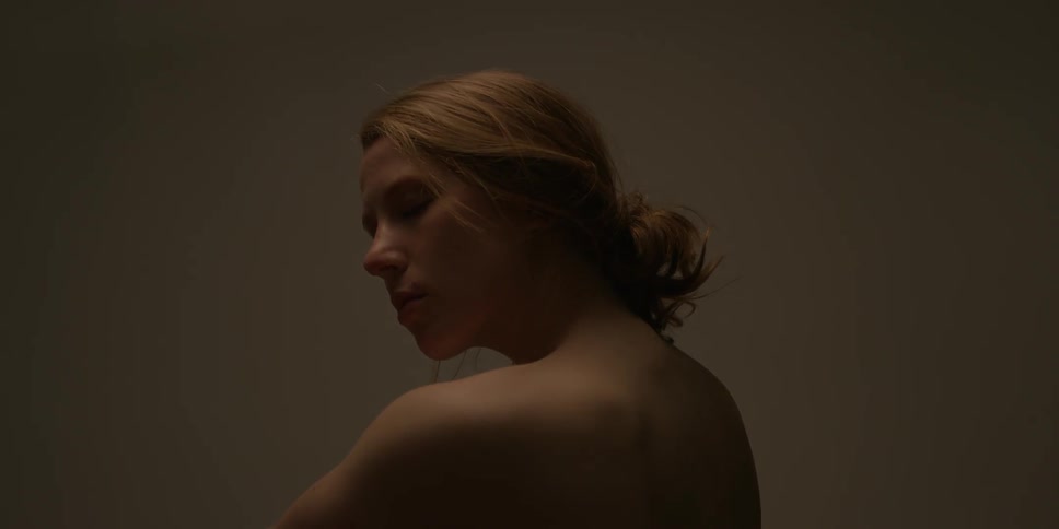 A woman stretches her neck and then holds her shoulder