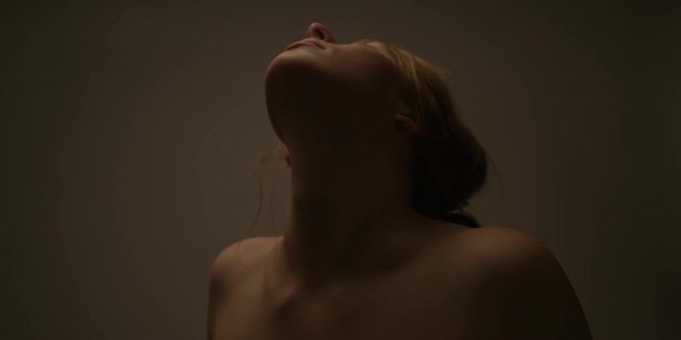 A woman without a shirt is stretching her neck, back and shoulders
