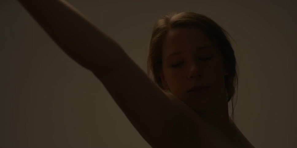 A naked woman lifts her arms up and stretches