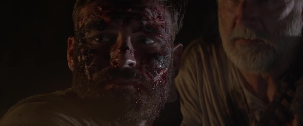 A man's face is covered with blood in a dark cave