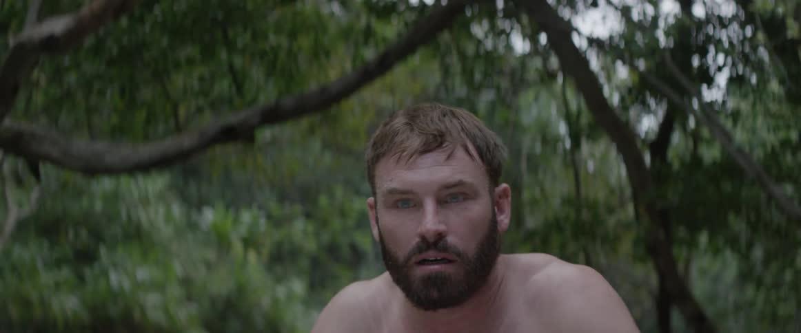 A man angrily tears his shirt off