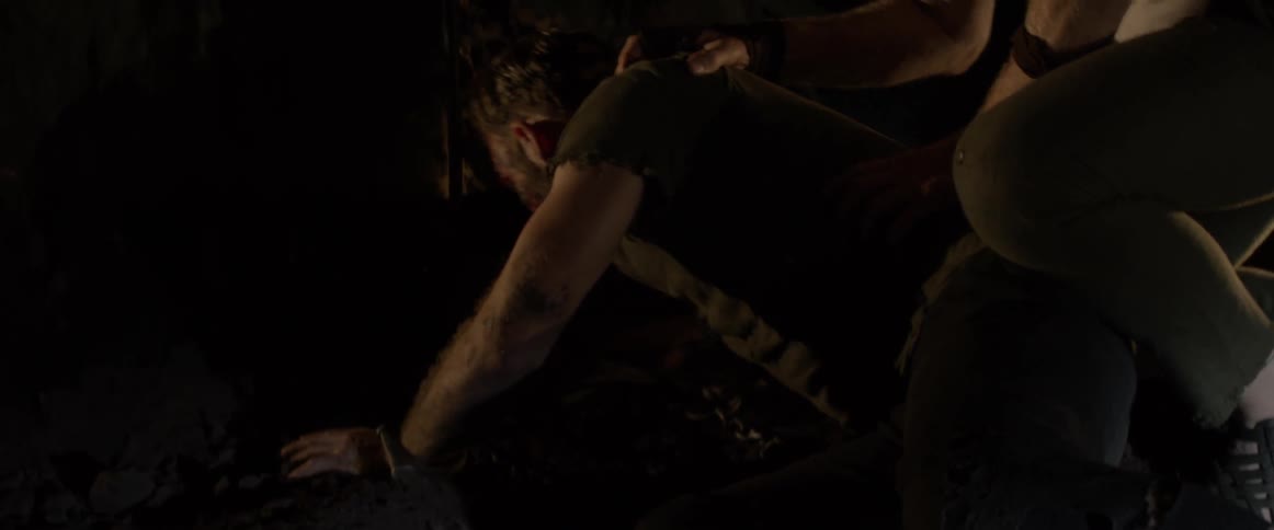 A man is woken up by another man in a dark cave