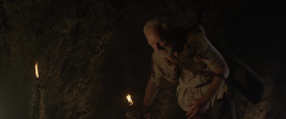 A man pulls a chain out of the wall then kneels beside a man