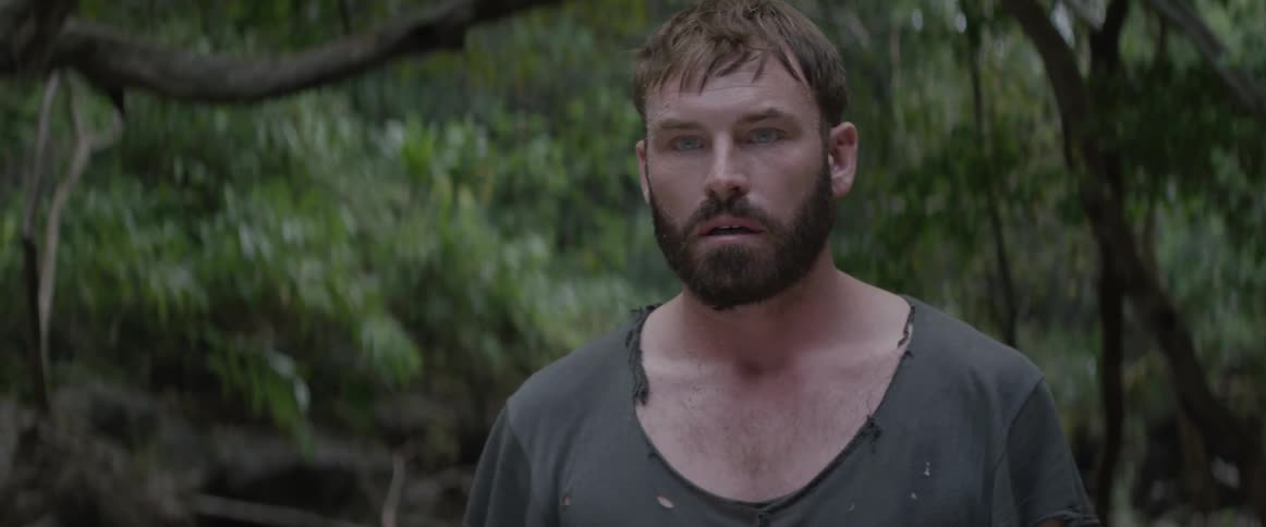 A concerned man wears a tattered shirt in a forest