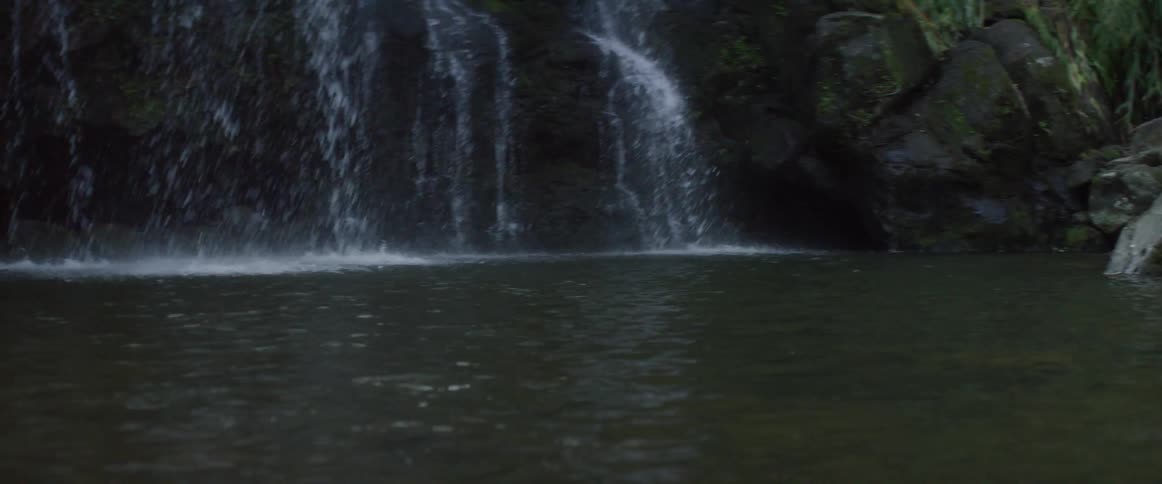 A waterfall is flowing into a natural pool with rocks