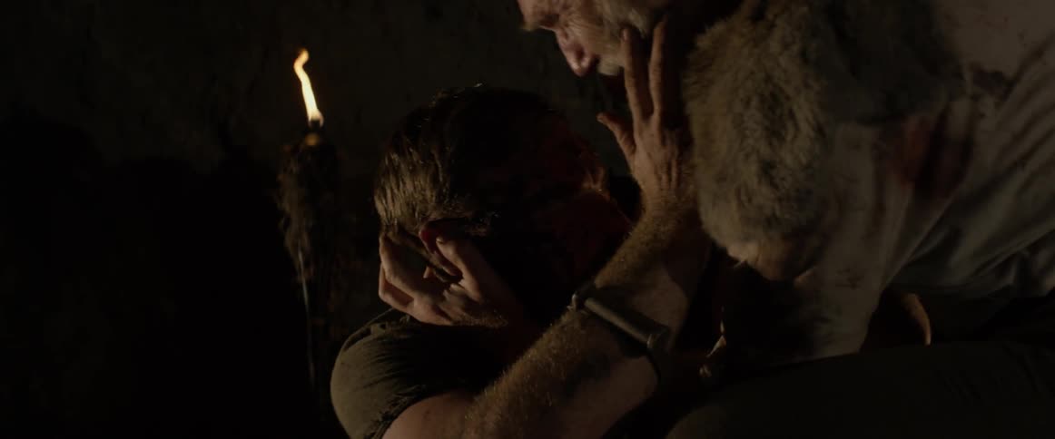 An injured man is comforted in a dark cave