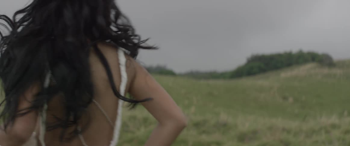 A woman looks over her shoulder and smiles as she runs in a natural setting