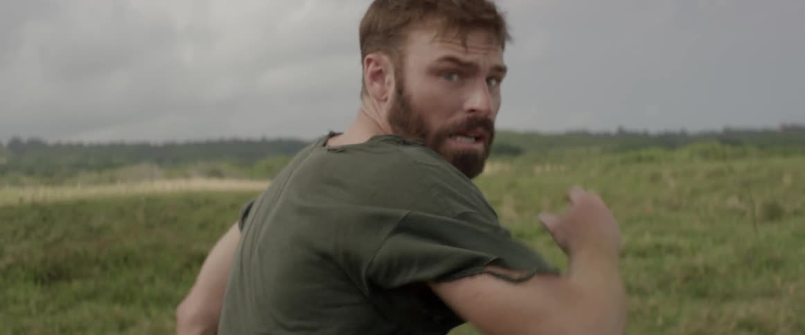 A scared man in a tattered shirt runs across a field