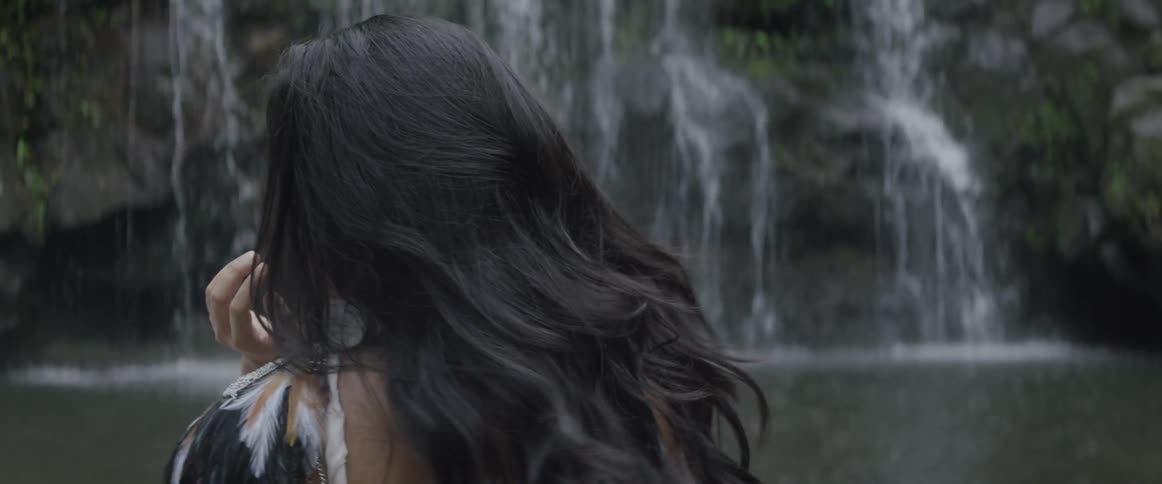 A woman standing by a waterfall looks over her shoulder