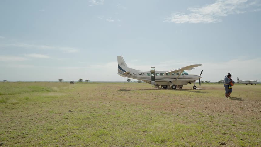 People walk away from a small plane while another lands
