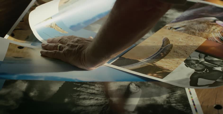 A person is leaning over photographs on the ground