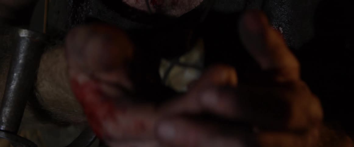Man holds a pendant with bloody hands