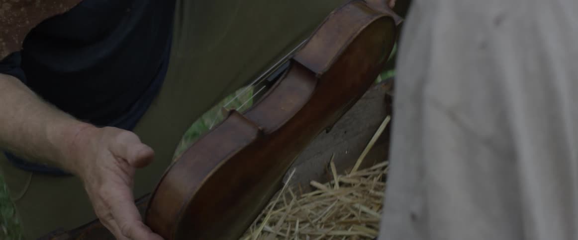 Man takes a violin out of a case and hands it to another person