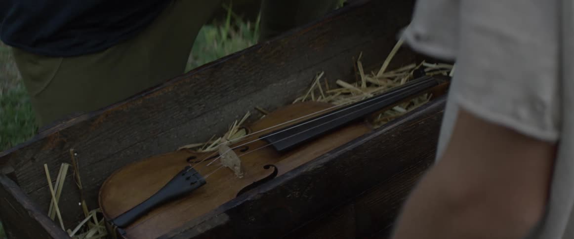 A man opens a wooden box revealing a violin