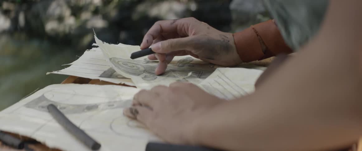 A person sketches with a charcoal stick