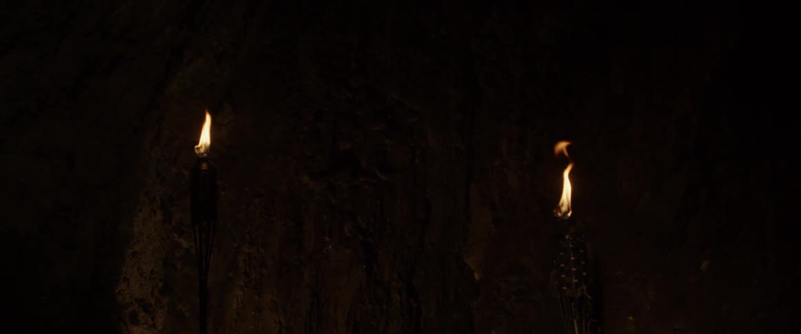 Tiki torches are lit inside of a cave