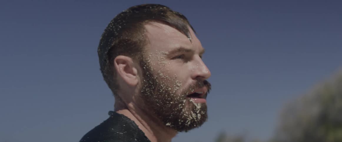 A man covered in water and sand looks around at his surroundings