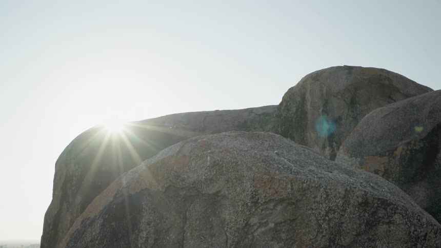 The rocks are very large and the sun is shining above them