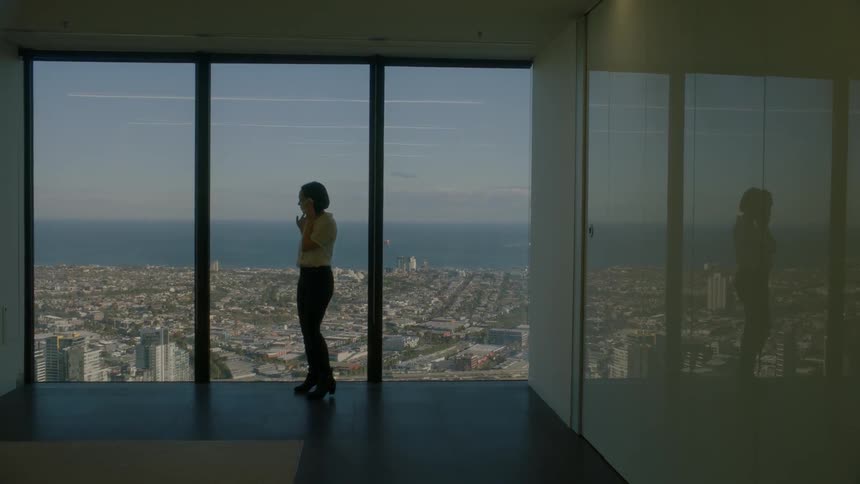 Woman stands by a window overlooking the bay