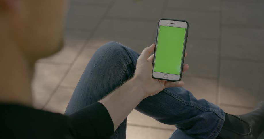 A person sits down looking at his phone