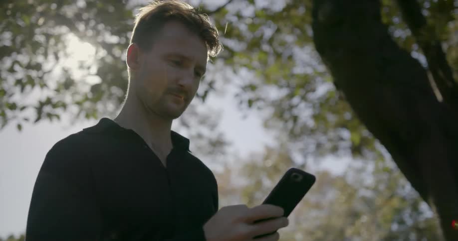 A man is using his cell phone on a windy day