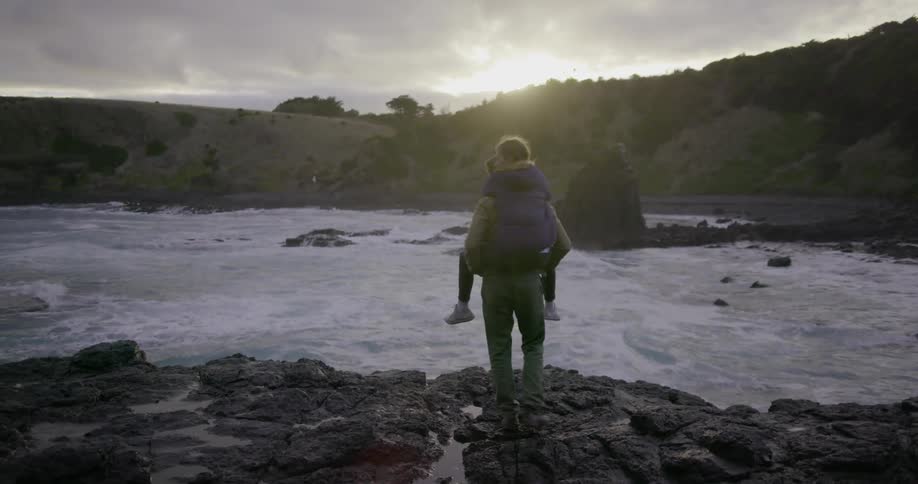 A man is giving a woman a piggyback ride to the edge of a river