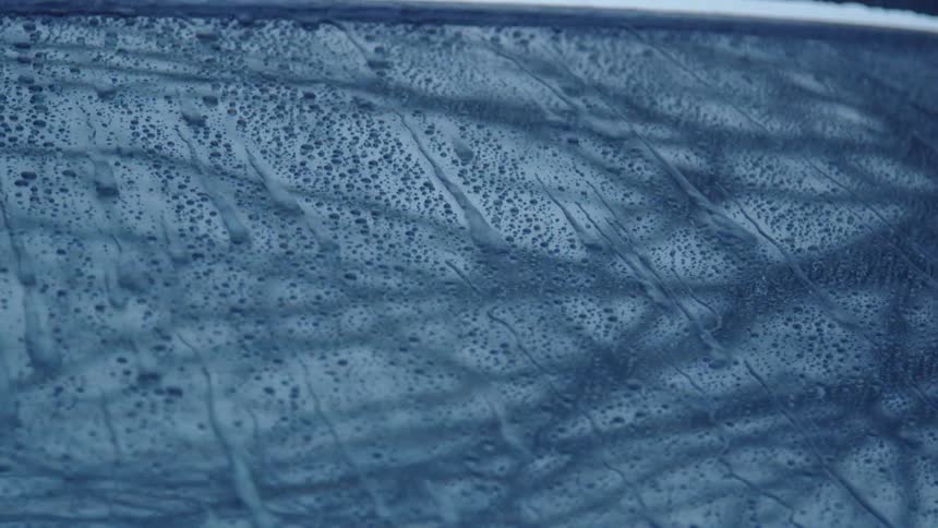 Rain runs down a car's windshield during a stormy day