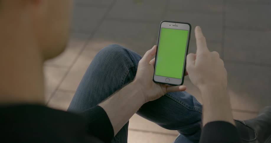 Person swiping up on their smartphone while sitting with their legs crossed