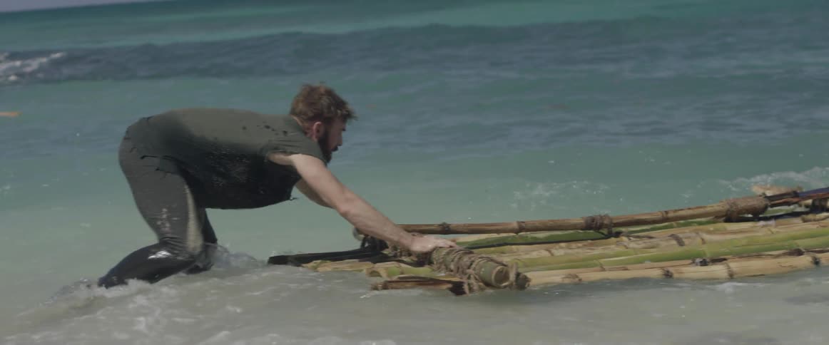 A castaway pulls a wood raft into the ocean