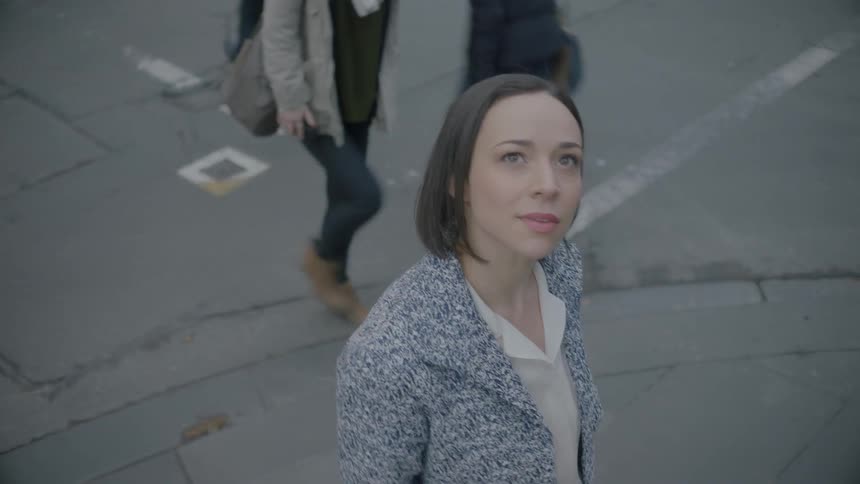 Woman looks up while walking down a crowded city street
