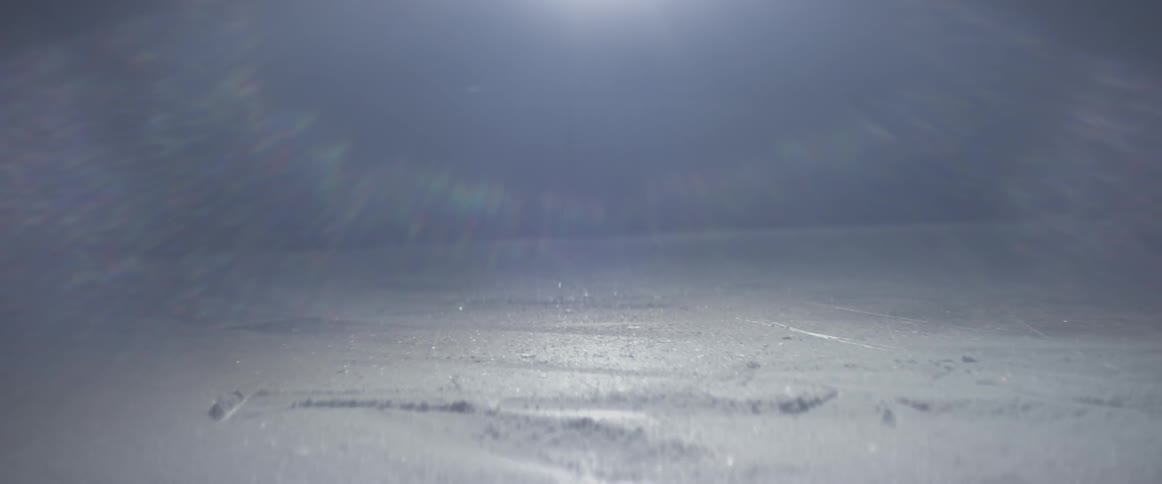 A hockey player skates and turns on the dark ice