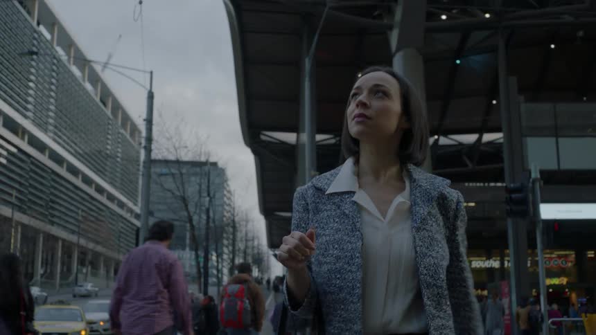 A woman walks down a city sidewalk