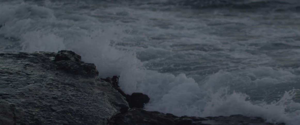 Water waves splashing up to a rocky shore