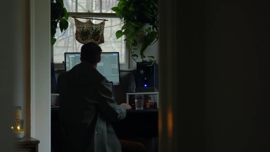 A man is using a computer at a desk in a home during the day
