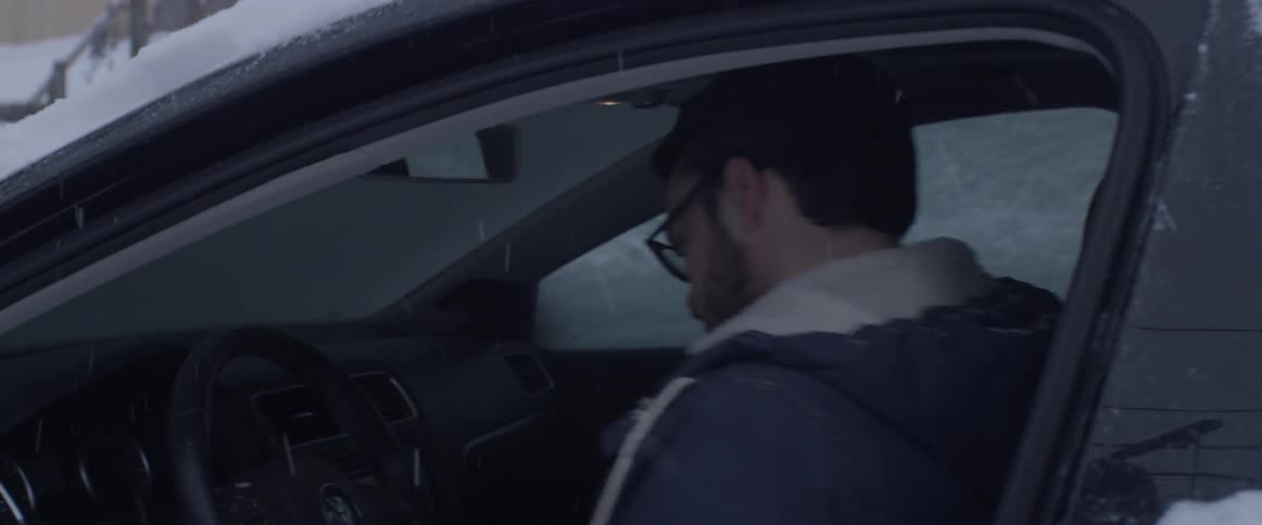 A man gets into a car covered with snow on a snowy day